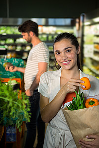 在有机区里拿着一个杂货袋的笑着女人的肖像杂货店女士购物职业顾客交易男人零售快乐蔬菜图片