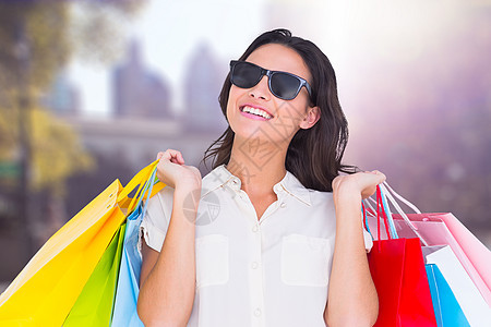 手持购物袋的微笑妇女太阳镜交通采购头发长发购物斑马线消费者零售摩天大楼图片