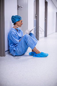 坐在地板上并使用数字石板的外科医生手术医务室磨砂膏沟通职业护士工作疾病职场走廊图片