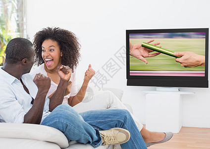 兴奋的一对情侣在电视上欢呼和看体育比赛行动享受感情运动员体操居所赛跑者家庭活动房子图片