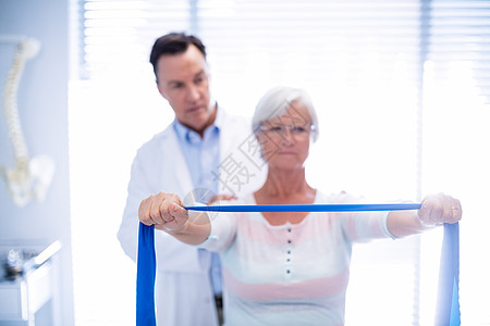 男性理疗师给高龄妇女做肩部按摩医院医疗外套医学咨询老年人女性病人医生治疗师图片