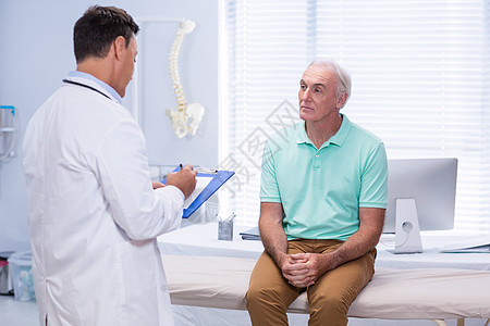 医生在诊所剪贴板上写作医学生理学老年人访问病人医院男性按摩师男人处方图片