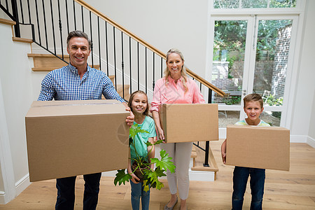 父母和孩子在家里起居室用纸板箱的搬迁儿子父亲兄弟男人女士公寓家庭微笑现实图片