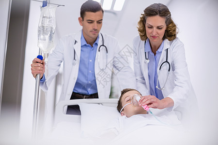 医生调整氧气面罩 同时在急诊室赶着病人女性医疗男生保健盐水照顾工作专家职业担架图片