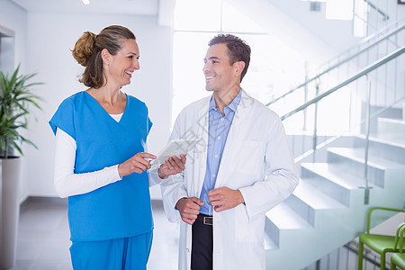护士和医生讨论数字平板电脑快乐职员服务职场女性工作同事走廊触摸屏男性图片