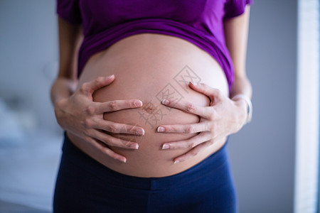 孕妇在病房中抚摸肚子的中段孕妇等待女性医务室腹部孕产休闲保健医学指导服装图片