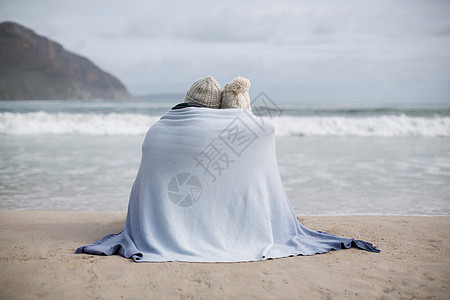 在海滩上用毯子包着一对成熟夫妇拥抱活力海岸线冬装娱乐亲密感力量夫妻男人女性图片