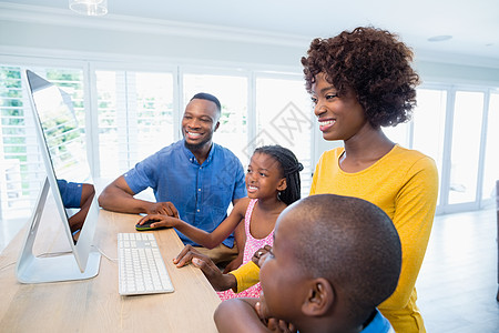 幸福的家庭在客厅使用计算机住所喜悦互联网闲暇桌子母亲享受女士男人家庭生活图片
