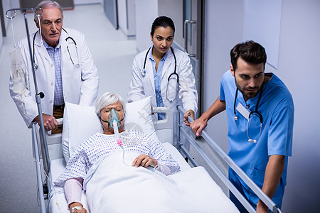 医生和护士在走廊推推紧急担架床男性肢体面罩保健男人女性疾病退休药品放射科图片