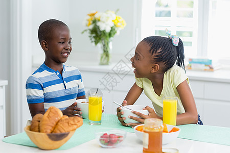 兄弟姐妹们在家餐桌上吃早饭吃饭牛奶微笑早餐兄弟姐妹饮料感情木瓜男性面包家庭图片