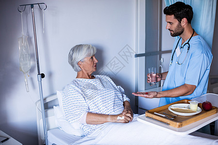 医生为床上女高级病人提供药物治疗女性放射科茶点咨询托盘果汁药品男性玻璃退休图片
