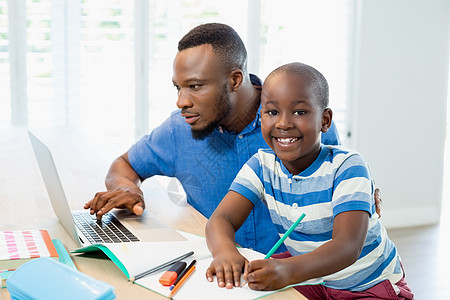 父亲使用笔记本电脑 儿子在客厅做功课亲密感互联网教育家庭生活闲暇男生孩子休闲房子沟通图片