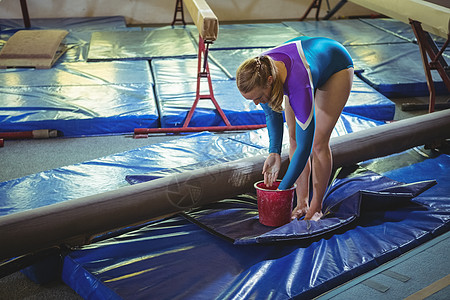 女体操运动员在练习前双手上施粉粉粉锻炼女性运动服运动灵活性体操粉笔粉专注健身房杂技图片