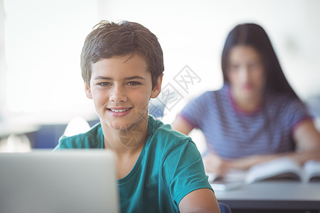 在课堂上使用笔记本电脑对快乐的学童的肖像青春期女学生长椅休闲闲暇同学学生服装沟通男生图片