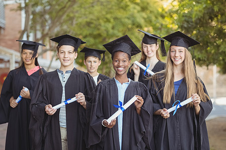 在校园里拿着学位卷轴站立的研究生生肖像女学生友谊成功闲暇礼服男生大学朋友们孩子快乐图片