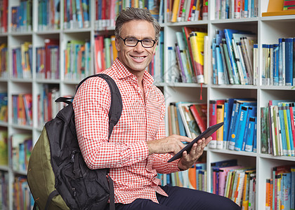 图书馆使用数字平板电脑对快乐学校教师的肖像职业微笑触摸屏休闲技术命令知识背包滚动互联网图片