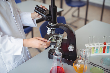 在实验室对显微镜进行女学生试验的中段部分图片