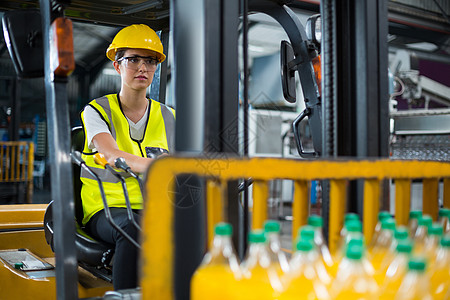 在工厂中驾驶叉车的女工厂工人果汁加载瓶子工作服现实职业制造业专注沟通屏幕图片
