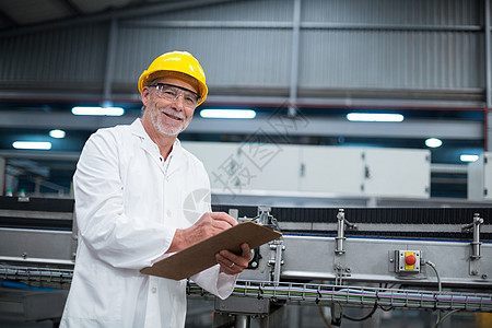 微笑的工厂工程师在工厂的剪贴板上维护记录工作商业快乐男人电脑生产线制造防护眼镜职业平板图片