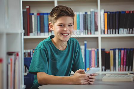 在学校图书馆里使用手机的男孩打笑学生男生服装中学笔记本教育青春期触摸屏知识快乐微笑图片