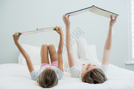 母亲和女儿躺在床上 阅读书上童年孕产乐趣喜悦被单女孩生活假期家庭孩子图片