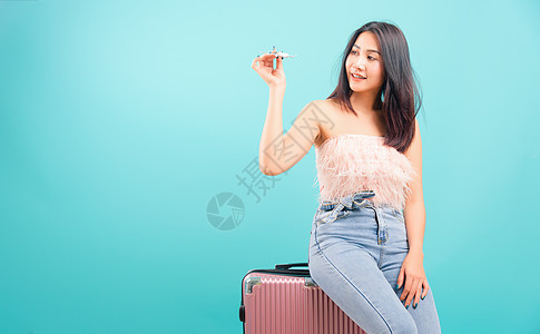 玩玩具飞机的肖像亚洲美丽的女人 模仿她的西式白色女士旅游蓝色运输手提箱游客旅行女孩工作室图片