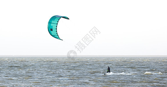 在海浪上漂浮着风筝锦标赛冲浪者男生活力绿色木板空气运动员背景图片