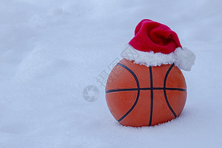 冬天在雪上戴着圣塔帽的篮子球图片