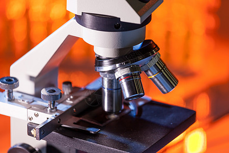 近距离的显微镜镜头 聚焦在温暖橙色光照下标本上生物烧瓶实验室工具样本玻璃放大镜教育卫生诊所图片