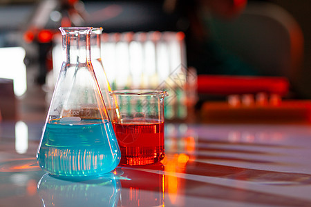 发光的实验室烧瓶 里面装满了五颜六色的化学溶液 桌子上有阴影 实验室 科学 化学概念橙子试管生物微生物学瓶子用具蓝色玻璃测试量筒图片