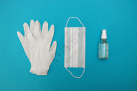 蓝色背景的防护性医用口罩 手套 酒精消毒剂 冠状病毒感染的概念 斗争 预防 检疫 从上面看 平躺标准皮肤病菌临床治疗研究微生物学图片