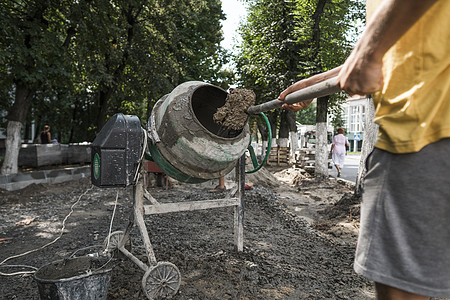 在人行道施工期间 建筑工人使用铲子在建筑工地的混凝土搅拌机中添加用于搅拌的配料技术收费工人旋转承包商木桶车辆建设者工具混合器图片