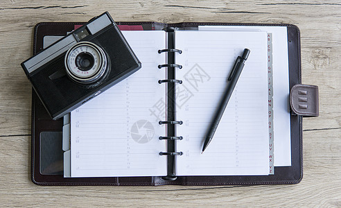 在木制背景上用笔和照相机打开棕色笔记本 白皮书 木桌子 小样 摄影笔记本图片