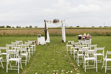 在一个领域的美好的婚礼与白色椅子 婚礼场地 婚礼拱门在户外的拱门两侧装饰着布料 鲜花和白色椅子花园桌子派对环境宴会天空公园仪式新图片