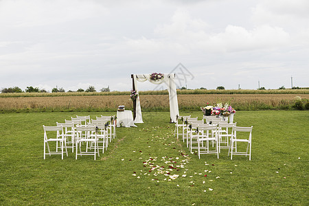 在一个领域的美好的婚礼与白色椅子 婚礼场地 婚礼拱门在户外的拱门两侧装饰着布料 鲜花和白色椅子接待海滩天空庆典仪式新娘假期环境婚图片