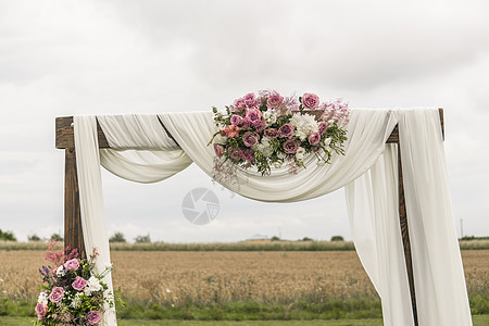 花岗木拱门 有白布和紫罗兰粉红色鲜红花 在一次生锈的婚礼上放绿色叶子传统晴天森林派对环境装饰婚姻接待草药风格图片