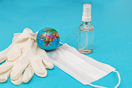 防护性医用口罩 手套 酒精消毒剂 蓝色背景的地球 冠状病毒感染的概念 斗争 预防 检疫 从上面看 平躺疫苗呼吸治疗临床微生物学喷图片