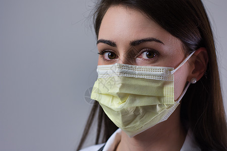 身戴黄色面罩的女医院工作人员 双眼遮盖可见 灰色背景孤立无援护理口罩诊所照顾者面具进阶把脉卫生病人博士图片