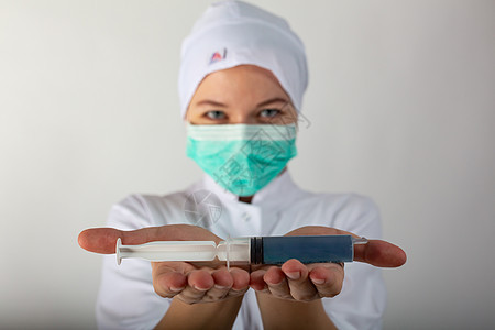 身穿医疗大衣的女孩持有一个大型注射器 配有蓝色液体冠状子疫苗感染流行病细菌疫苗注射女士免疫科学医院医生图片