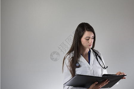 女性保健专业检查员在灰色背景上孤立的病人病历表 颈部围着止步镜 穿白色外套并扣上锁保健老年护士把脉药品考试医学医生医师血压图片