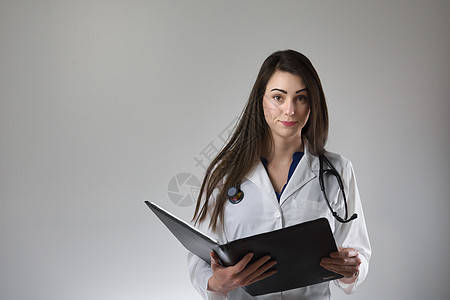 女性保健专业检查员在灰色背景上孤立的病人病历表 颈部围着止步镜 穿白色外套并扣上锁考试护士卫生照顾者助理药品医生女士医师博士图片
