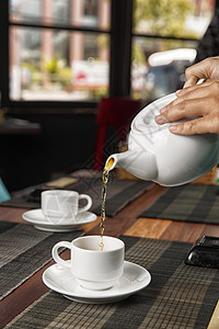 从茶壶里倒茶杯味道饮料陶瓷制品桌子杯子时间厨房香气液体图片