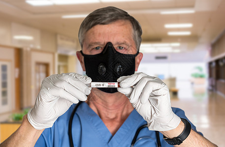戴面罩并持有科罗纳病毒检测结果的高级男医生背景图片