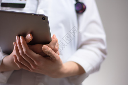 医疗保健专业人员手中的平板电脑近距离 白大衣 听诊器和徽章在背景中可见 执业护士或 PA 的手使用医学技术为患者服务医生屏幕保健图片