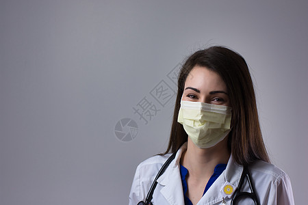 在灰色背景上与白大衣 听诊器和黄色个人防护设备面具相隔离的可视面部; 显见图片