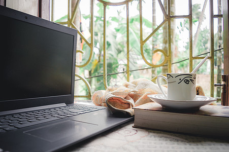 一杯咖啡一本书和笔记本电脑在早晨的窗户阳光下 保持社交距离期间的日常工作 待在家里 在家工作 远程工作和业务连续性背景饮料隔离技图片