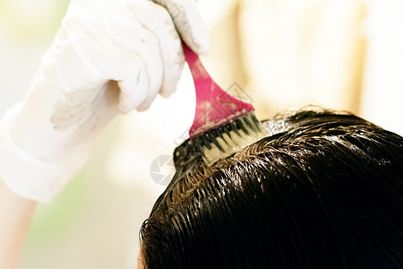 一名年轻妇女在用刷子染发和戴乳胶手套时染发治疗理发师造型师女性染料工具化妆品沙龙女士造型图片