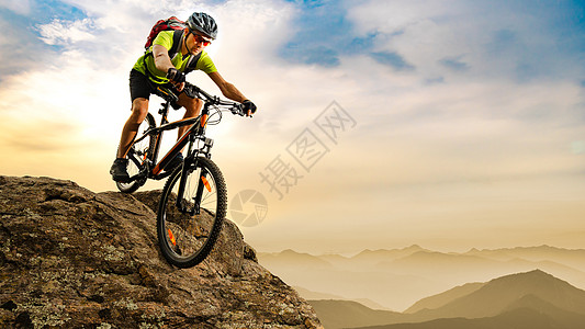 赛车手骑着摩托在山上日出时的岩石落下 极端运动和概念图片