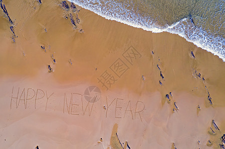 由海浪和手写的新年快乐拍摄的空中顶楼海滩问候海洋天线粮食问候语图片