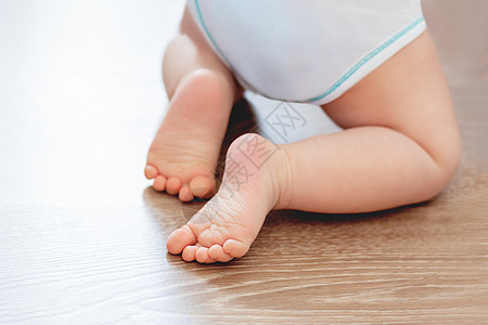 婴儿脚踩在木地板上 小孩穿着白体衣和尿布的紧跟鞋 在家睡得很舒服图片